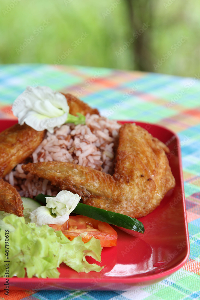 Thai style food, the deep fried chicken wings with rice, soup, vegetable and fruit on red plate. Thai style food, the deep fried chicken wings with rice, soup, vegetable and fruit on red plate.
