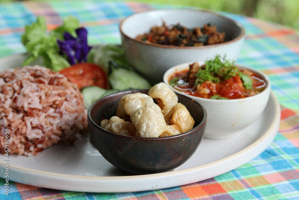 Thai style food, rice with stir fried basil with pork, chili paste, pork kappa and vegetable on white plate. Thai style food, rice with stir fried basil with pork, chili paste, pork kappa and vegetable on white plate.