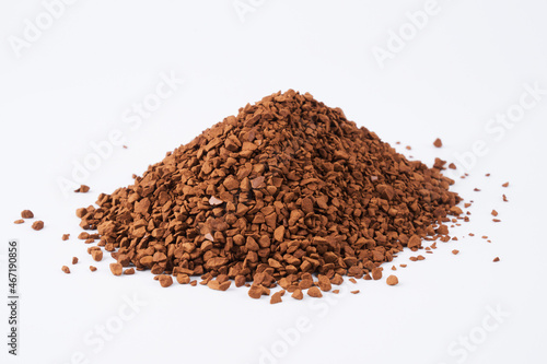 Freeze-dried instant coffee on white background close-up. Heap of powdered brown coffee product scattered on the table