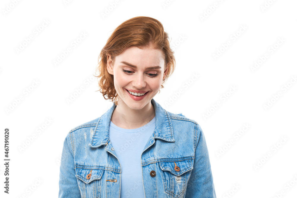 Portrait of a young red-haired girl on a white isolated background in jeans. Looks into the camera Portrait of a young red-haired girl on a white isolated background in jeans. Looks into the camera