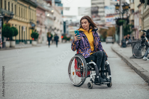 Woman in wheelchair using a smartphone while out in the city