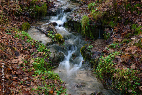 beautiful waterfall in a mountain valley with brown leaves on green grass in autumn.long exposure