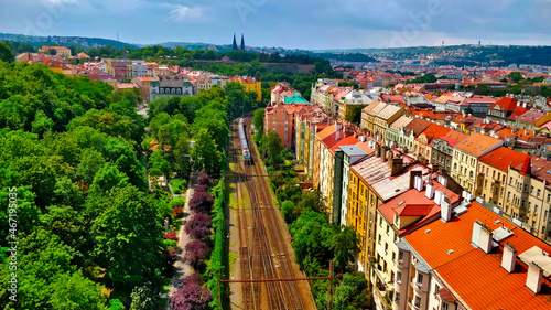 Railroad dividing city from forest seen from bridge with castle in horizon.