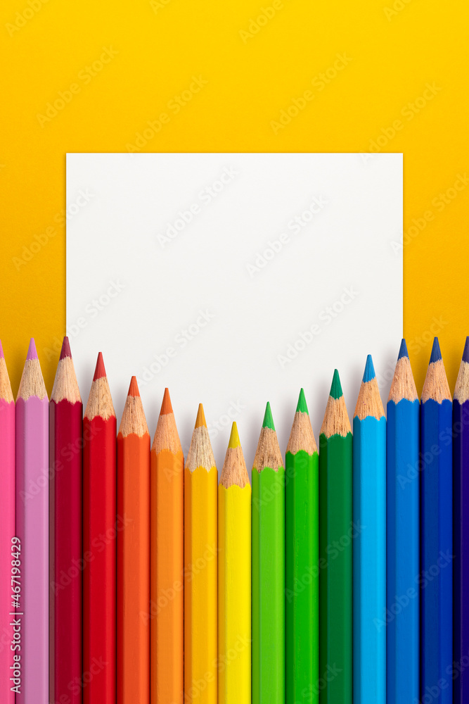 Creative layout made of color pencils on yellow paper background with white paper card note. Flat lay. Education concept. Creative layout made of color pencils on yellow paper background with white paper card note. Flat lay. Education concept.