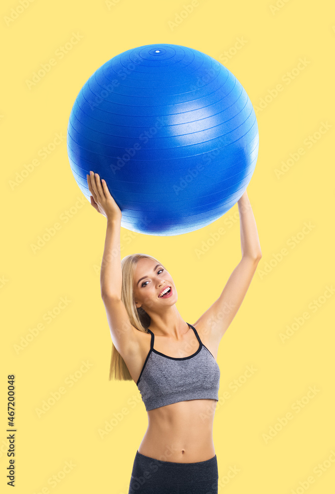 Portrait of happy excited blond young woman in sportswear with fitball, isolated over yellow color background. Fitness, exercising and fit gym concept. Portrait of happy excited blond young woman in sportswear with fitball, isolated over yellow color background. Fitness, exercising and fit gym concept.
