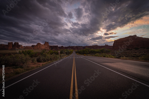 Long desert road in the middle of nowhere under moody dramatic stormy sunset sky