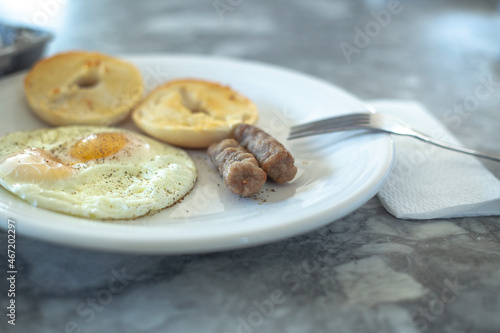 Egg sausage and bagel toast with ground black pepper on a breakfast plate.