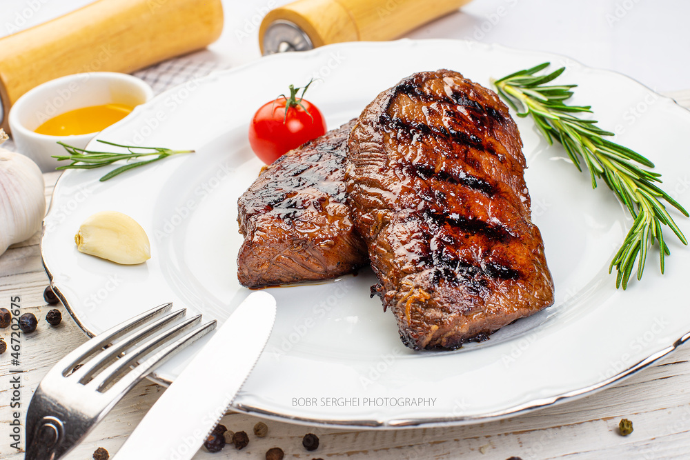 Piece of roast beef with spices served on white plate Piece of roast beef with spices served on white plate