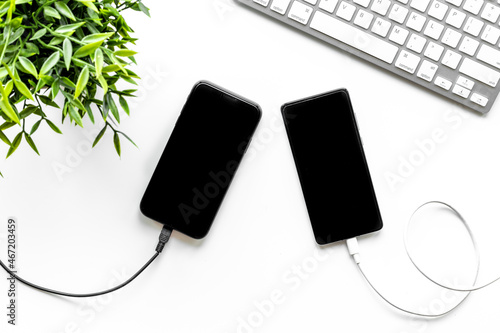 Cables for charging smartphone or laptop on office table, top view