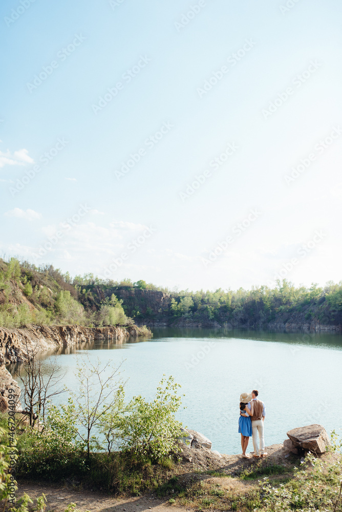 a young couple a guy and a girl are walking near a mountain lake surrounded