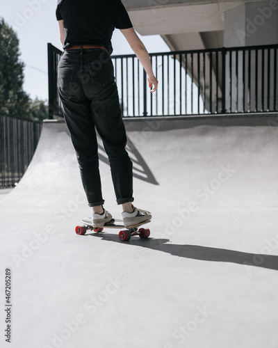 A European female skater with red hair is riding a skateboard on a skate pad. a woman in black clothes and a skateboard or a longboard is engaged in active sports. extreme sports roller skates or