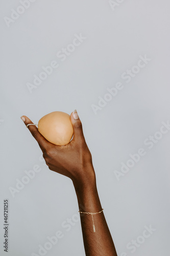 Black hand holding a pear wearing a gold bracelet photo