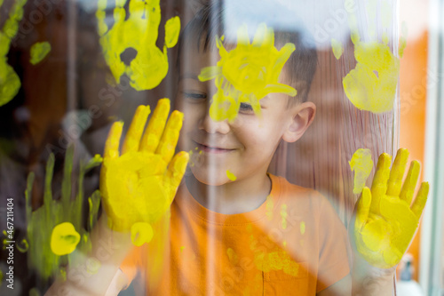 Boy printing window glass with yellow paint