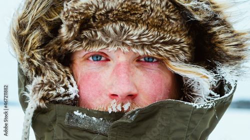 Close-up of man with blue eyes wearing parka jacket and covered with snow photo