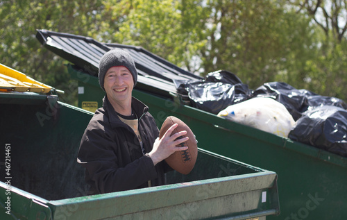 man holding football while standing in a dumpster photo