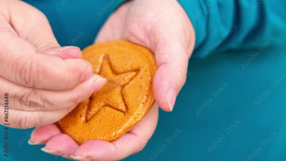 closeup female hand scratches with needle yellow caramel sugar cookies with embossed star for popular Korean children's game, cut out figure with needle, do not crumble pattern, holiday homemade food closeup female hand scratches with needle yellow caramel sugar cookies with embossed star for popular Korean children's game, cut out figure with needle, do not crumble pattern, holiday homemade food
