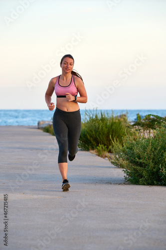 young woman running along the boardwalk at sunset © Ekaitz