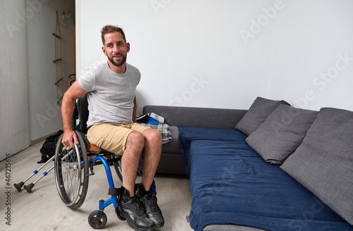 man in a wheelchair in his living room in front of a blue sofa