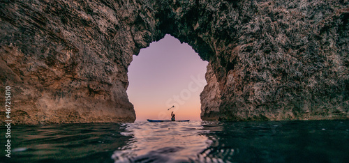 One person on paddle under huge rock