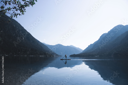 Person kayaking in lake surrounded by mountains