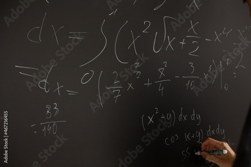 Person witting mathematic equation on chalkboard