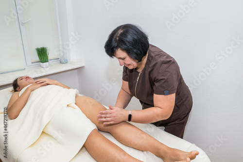 woman masseur massages legs of a young girl in a massage parlor.