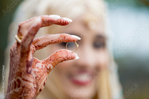 Woman's hands with henna tattoo on them holding ring photo