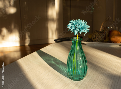 Creative idea sunny day. Blue vase with blue flower on the table.