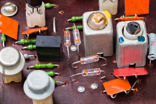 Obsolete electronic components on a circuit board of old radio. Retro germanium transistors and diodes, electrolytic and ceramic capacitors or carbon resistors. Aluminum coils with screw ferrite core.