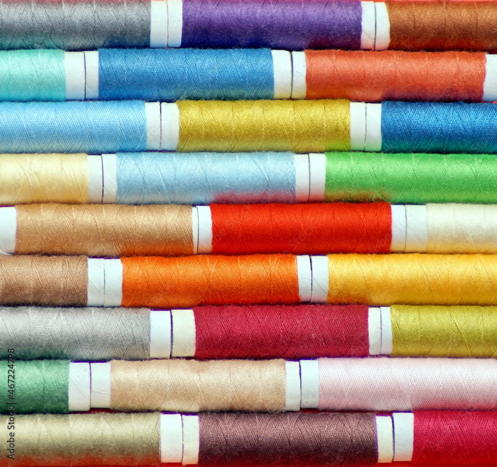 macro shot of rows of spools of multicolored sewing thread, laid alternately, with an offset. photo square macro shot of rows of spools of multicolored sewing thread, laid alternately, with an offset. photo square