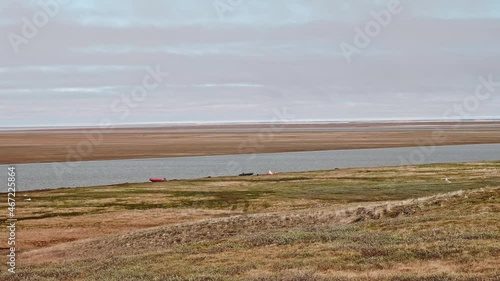 View of landswell of Yamal peninsula and Kara sea. Boats of hydrologists are on the shore. Cloudy afternoon photo
