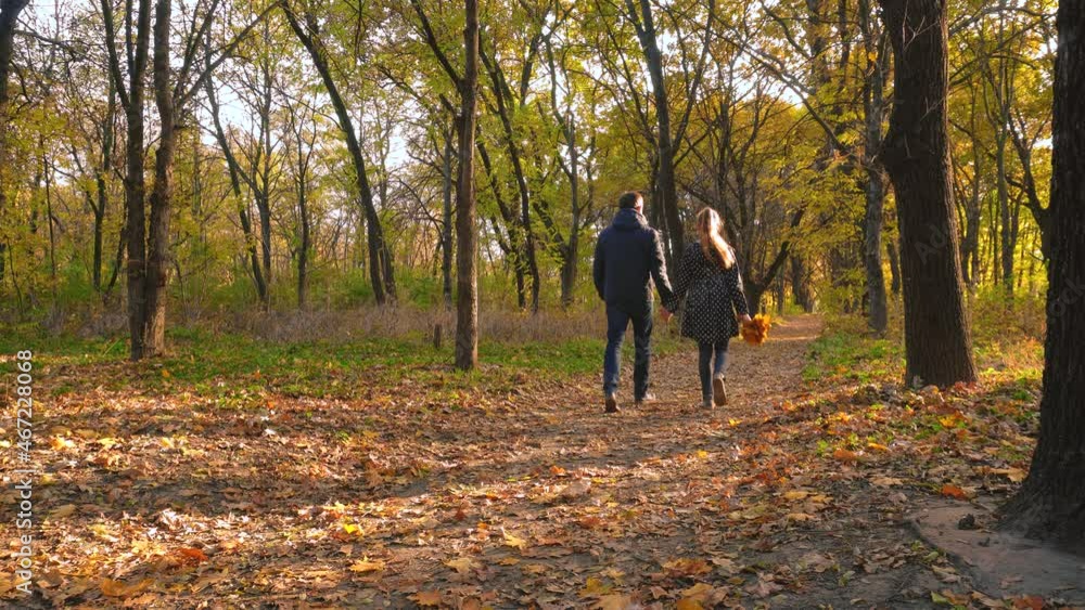 Father and daughter with a bouquet of autumn leaves are walking along a path in the autumn forest. Walk in the autumn forest. Beautiful autumn nature. Father and daughter with a bouquet of autumn leaves are walking along a path in the autumn forest. Walk in the autumn forest. Beautiful autumn nature.