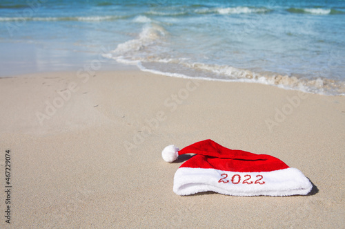 New Year 2022 written at the Santa Claus hat on caribbean beach.