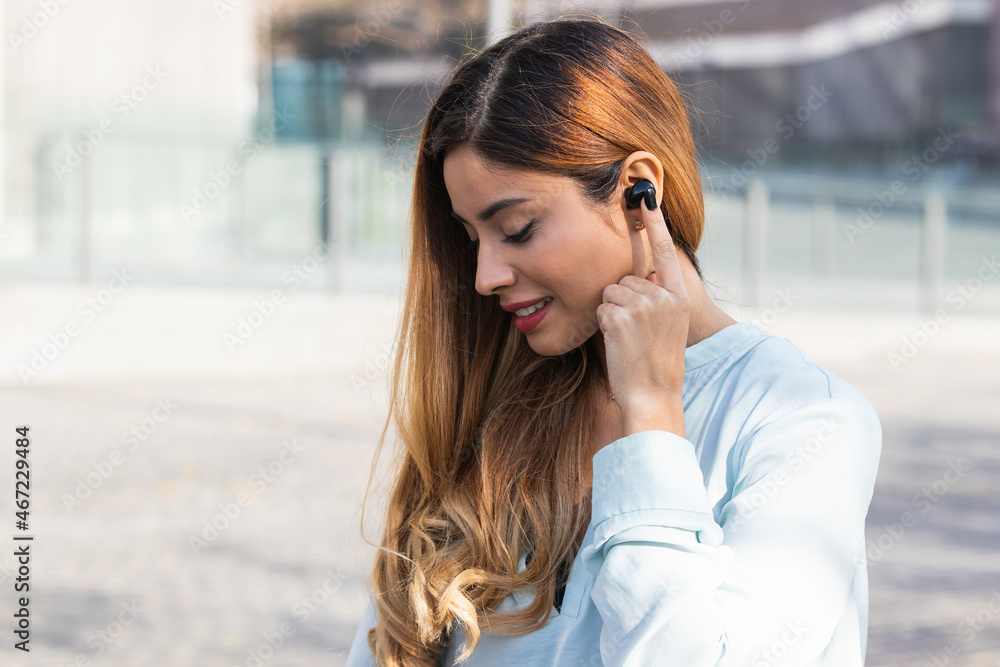 Portrait of young brunette business woman outdoors using earphones while working. Business concept Portrait of young brunette business woman outdoors using earphones while working. Business concept