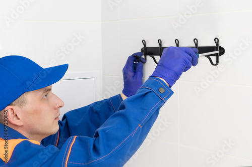 the worker makes installation of a hanger on a wall in a bathroom
