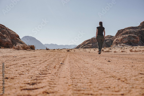 A sportily dressed girl walks along an empty road in the Wadi Rum desert, sunny clear day, Jordan photo