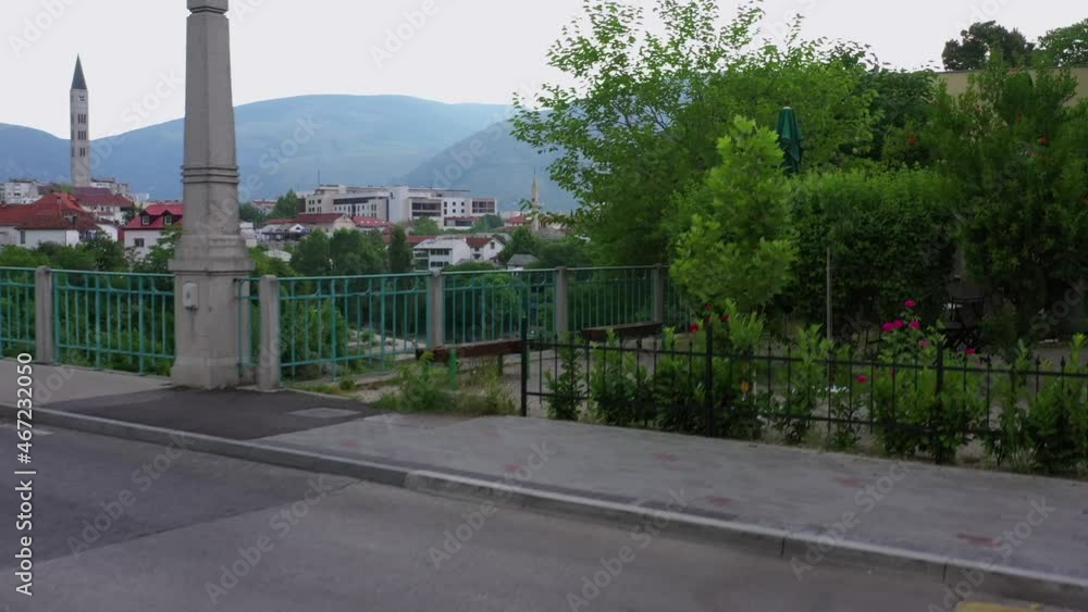 Aerial: Beautiful Shot Of Structures In City Against Mountains, Drone Descending Over Road - Mostar, Bosnia and Herzegovina Aerial: Beautiful Shot Of Structures In City Against Mountains, Drone Descending Over Road - Mostar, Bosnia and Herzegovina