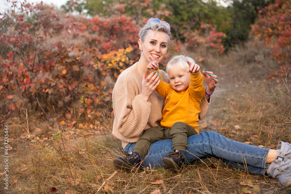 mother kissing her child in autumn background with golden and red trees