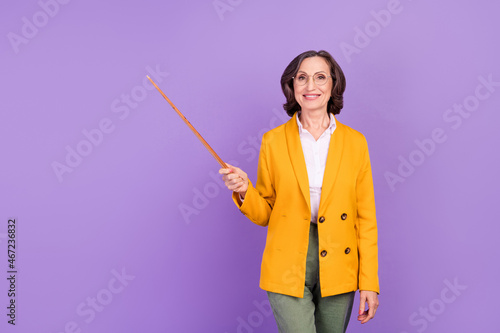 Photo of smart lecturer grey old lady hold indicate empty space wear yellow jacket isolated on purple color background