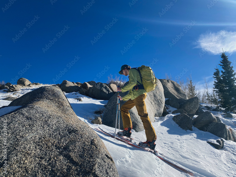 Naklejka premium Man backcountry skiing in a rocky area on a sunny day