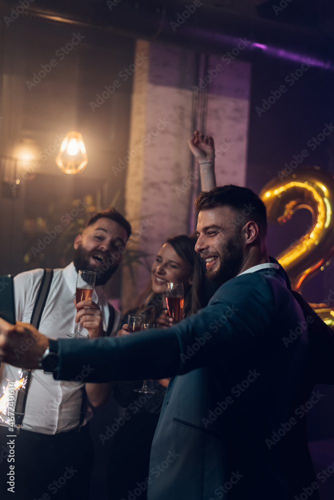 Happy group of friends celebrate New Year's Eve and taking selfie with a smartphone
