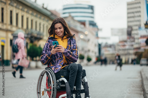 Woman in wheelchair using a smartphone while out in the city photo