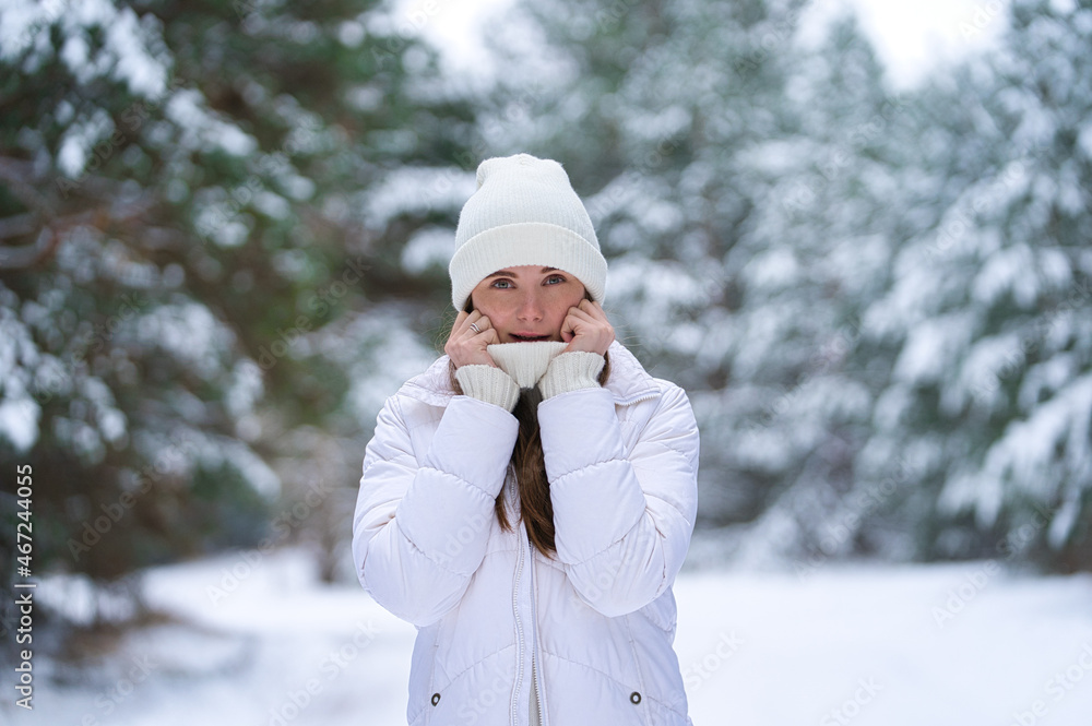 Close up portrait of happy girl in sweater and a knitted hat enjoying winter moments, having fun on a snowy morning on a blurred background of wood Close up portrait of happy girl in sweater and a knitted hat enjoying winter moments, having fun on a snowy morning on a blurred background of wood