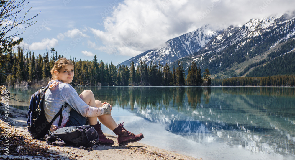 woman sitting next to a mountainous lake