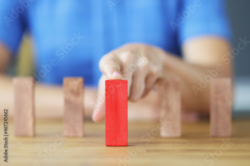 Female hand choosing red block among wooden closeup