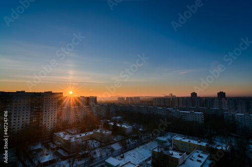 sunrise with light pillar over frosty city in winter © vasvormich