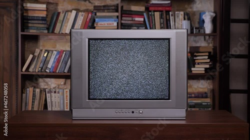 Old books background retro television set. Bad television signal noise. Room old tv set. 90s retro tv screen static noise. Analog static effect retro tv room interior home library bookshelf background