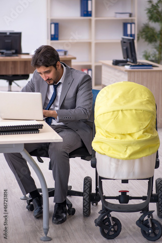 Young male employee looking after new born at workplace