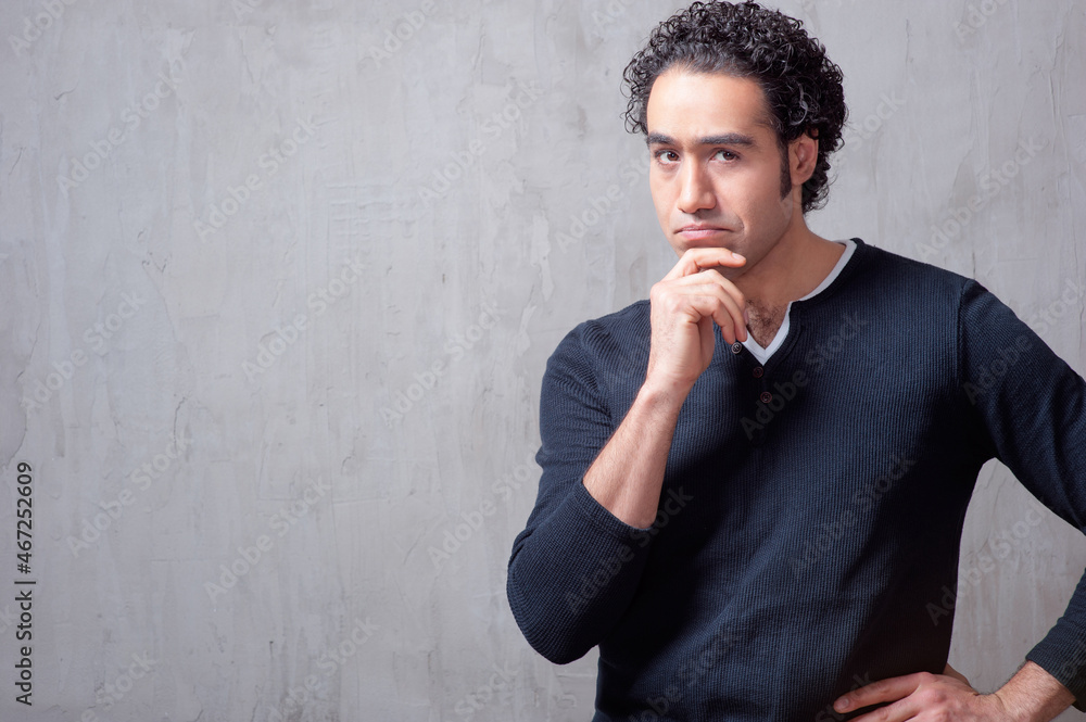 thoughtful young man in casual wear holding hand on chin thoughtful young man in casual wear holding hand on chin