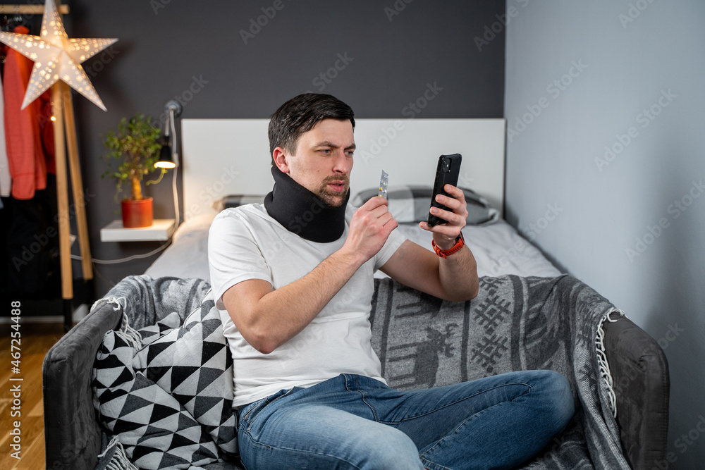 Fototapeta premium Man after accident in cervical collar consults online video call with doctor and receives recommendations for taking medications. Male in foam cervical spinal injury video conferencing with insurance